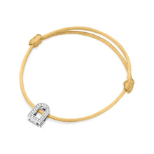 Load image into Gallery viewer, The L'Arc Voyage Charm PM bracelet from a Paris Atelier showcases an exquisite design with its 18k white gold lock charm adorned with Galerie diamonds. The silk cord in a delicate yellow hue is elegantly tied with adjustable knots, making it both simple and sophisticated.
