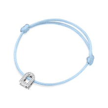Load image into Gallery viewer, Introducing the L'Arc Voyage Charm PM, an elegant bracelet crafted by Paris Atelier. It features a light blue silk cord with adjustable knots and is adorned with a small, horseshoe-shaped charm made of 18k white gold. The charm sparkles with Galerie Diamonds, offering a look reminiscent of classic diamonds.
