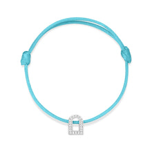 Load image into Gallery viewer, The L'Arc Voyage Charm PM bracelet showcases a turquoise silk cord with an adjustable knot design, featuring a striking 18k white gold padlock charm adorned with Galerie diamonds. Crafted with precision at the Paris Atelier, this charm is elegantly centered on the simple yet graceful cord.
