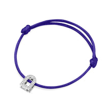 Load image into Gallery viewer, The L'Arc Voyage Charm PM bracelet showcases a vibrant purple silk cord with adjustable knots and features an 18k white gold charm shaped like a padlock, adorned with Galerie diamonds. Crafted with exquisite attention to detail, this piece mirrors the elegance of fine jewelry from a Paris atelier.
