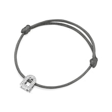 Load image into Gallery viewer, The L'Arc Voyage Charm PM bracelet features a gray silk cord with an adjustable knot design, showcasing a small U-shaped charm made of 18k white gold at the center. This charm is beautifully adorned with Galerie diamonds, adding a touch of luxurious elegance to any ensemble. Crafted by Paris Atelier, it seamlessly combines sophistication and style.
