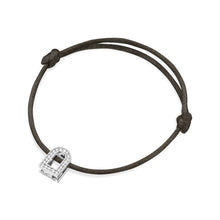 Load image into Gallery viewer, The L'Arc Voyage Charm PM bracelet features a sleek black silk cord with an 18k white gold lock charm adorned with Galerie diamonds. This chic accessory from the Paris Atelier is adjustable with knots on either side of the charm.
